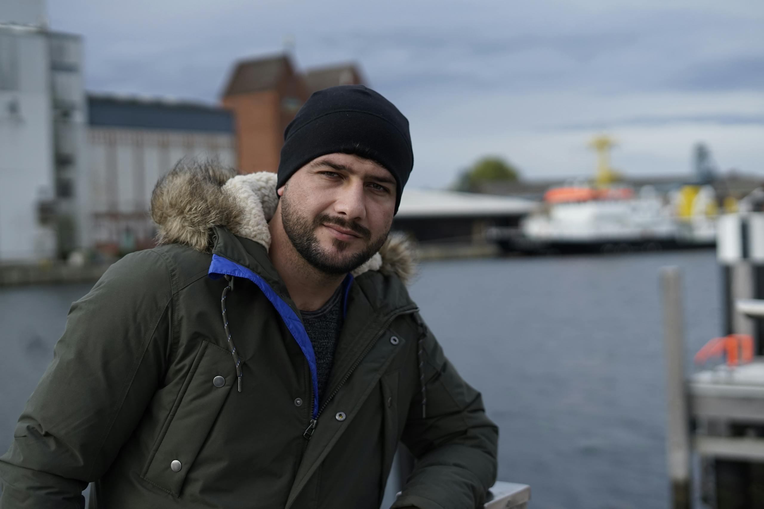 Bearded man in a warm jacket enjoying a scenic waterfront in Bocholt, Germany.