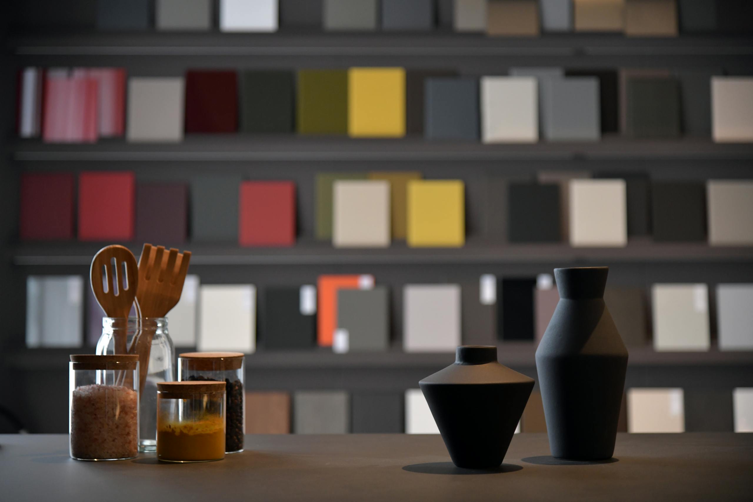 Kitchen utensils and jars on a counter against a backdrop of vibrant color samples.
