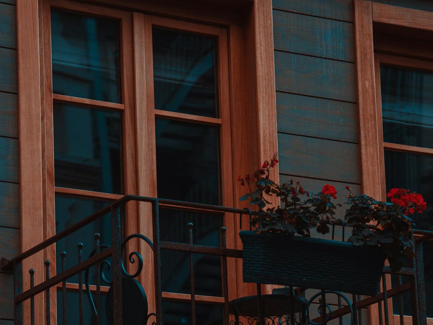 Cozy urban balcony with red flowers and decorative railing, creating a romantic atmosphere.